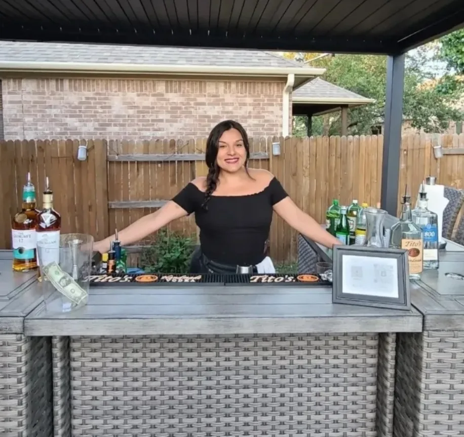 Bar Divas bartender at a covered outdoor patio bar with bottles, mixers, and bar tools arranged for service